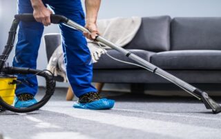 This image shows a man using a vacuum to clean a carpet.