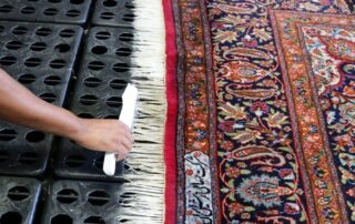 This image shows a man brushing an oriental rug.